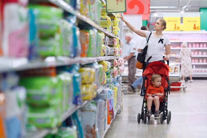 A woman pushing a child in a stroller shops for diapers