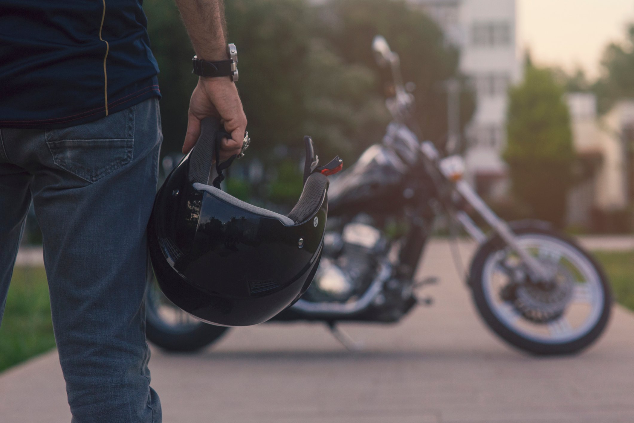 Man with motorcycle helmet and a bike in the background. 