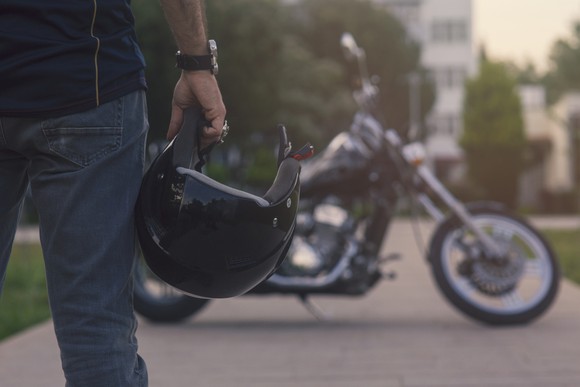 Man with motorcycle helmet and a bike in the background. 