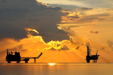 An oil rig and platform at sunset.