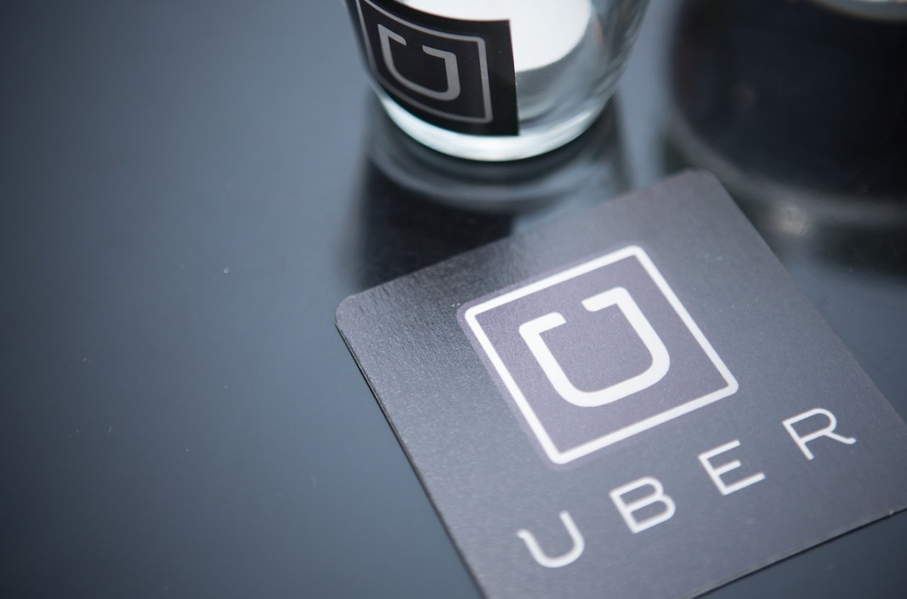Coaster and glass with Uber logo on a black table.