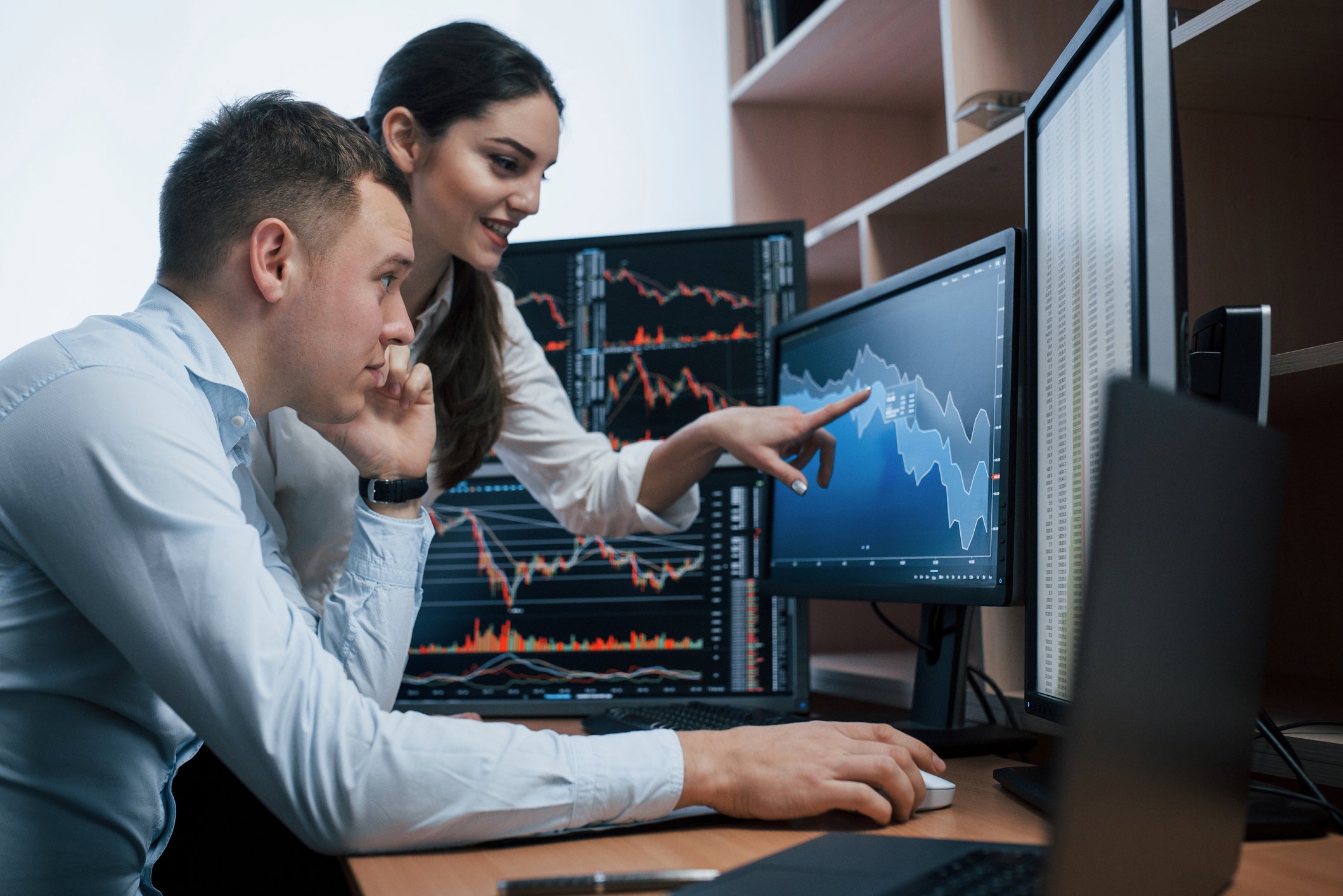 Two people look at a financial chart on a computer screen.