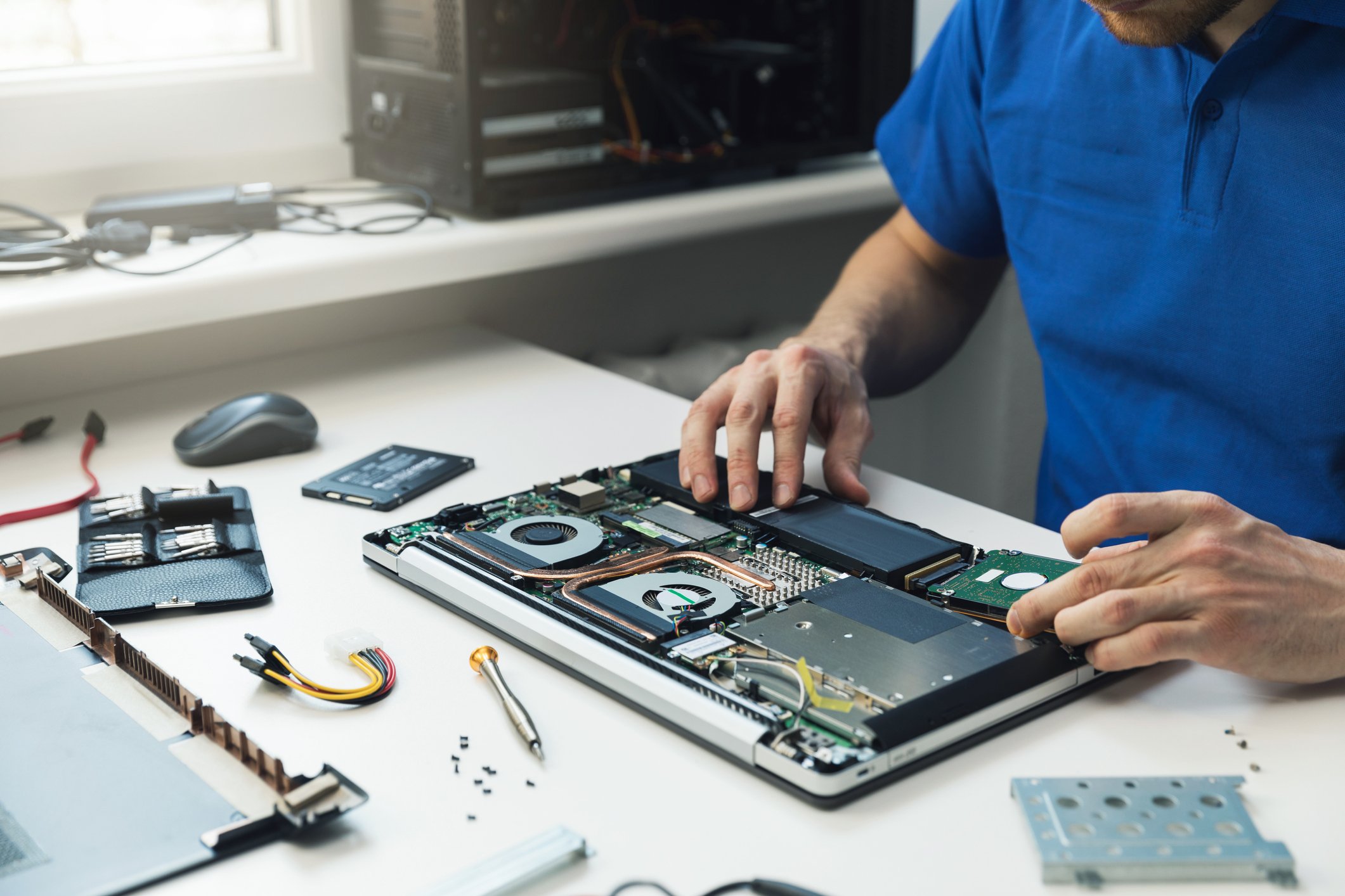 A man at a desk assembling a laptop