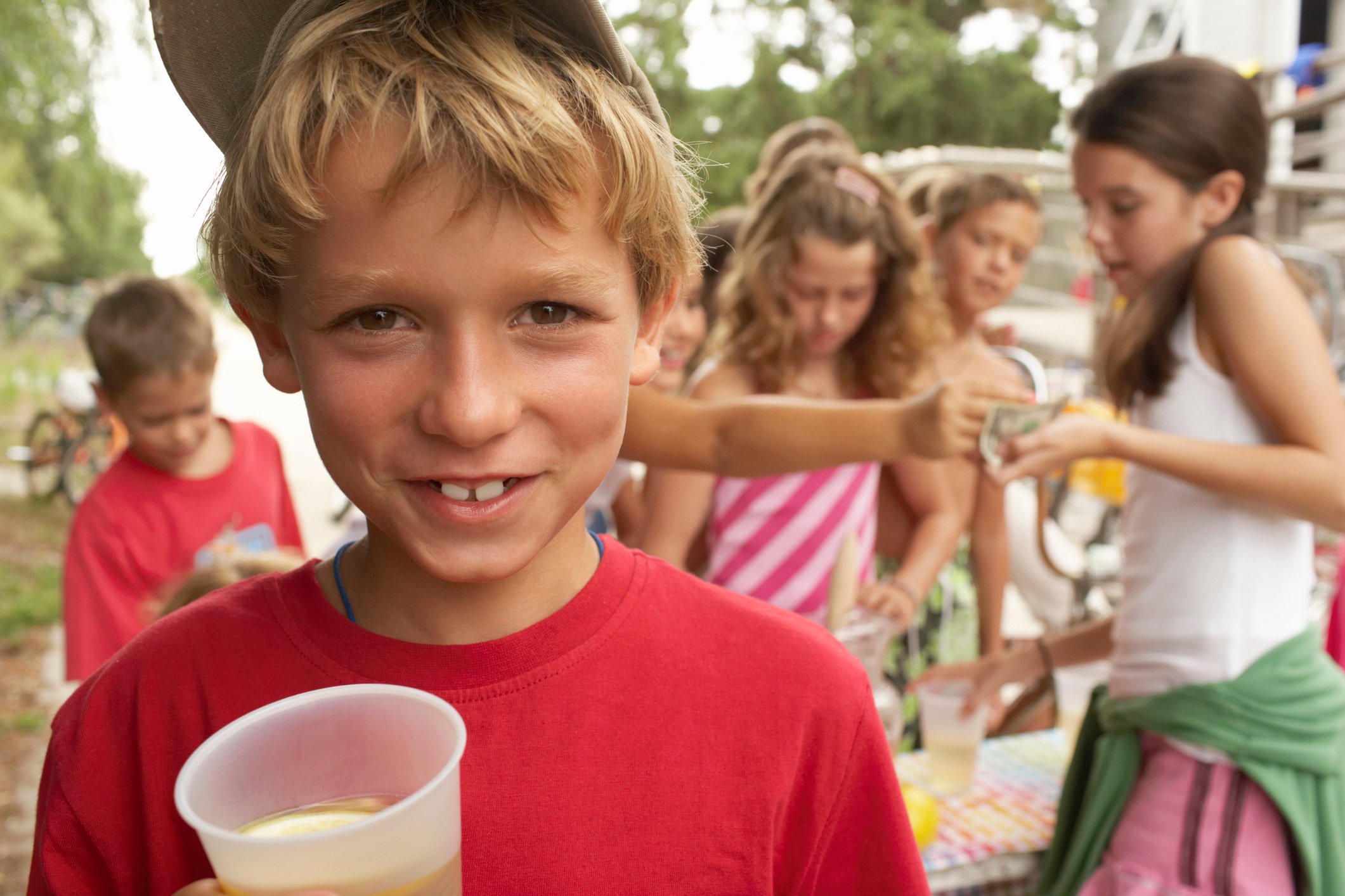 Boy smiling with lemonade stand in background