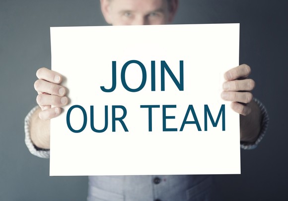 A man holds a sign saying join our team.