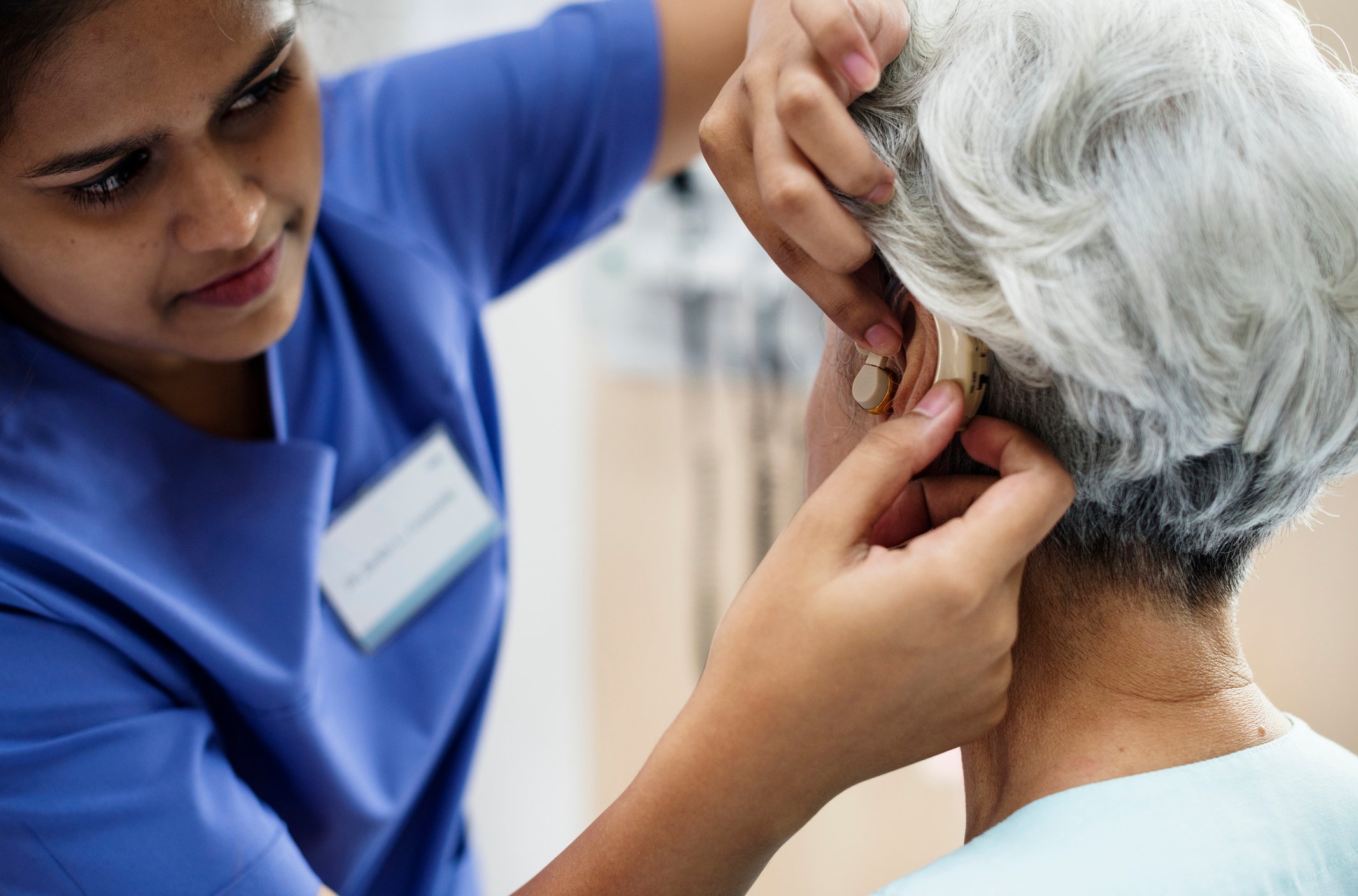 A technician helps a woman with her hearing aid