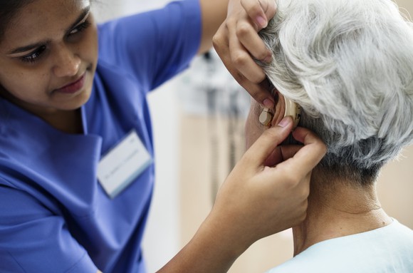 A technician helps a woman with her hearing aid