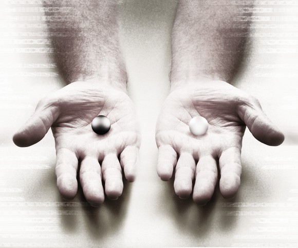 Two hands holding different-colored marbles