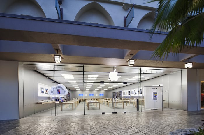 Apple Store location on first floor of an outdoor center with palm tree outside.