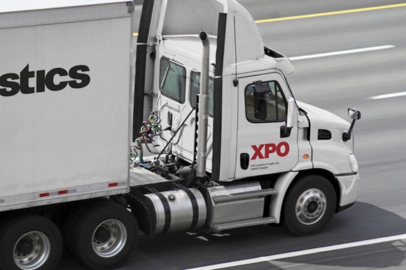 White truck with XPO branding on the side in the right lane of a four-lane highway.