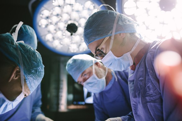 Surgeons in operating room with lights over their heads.