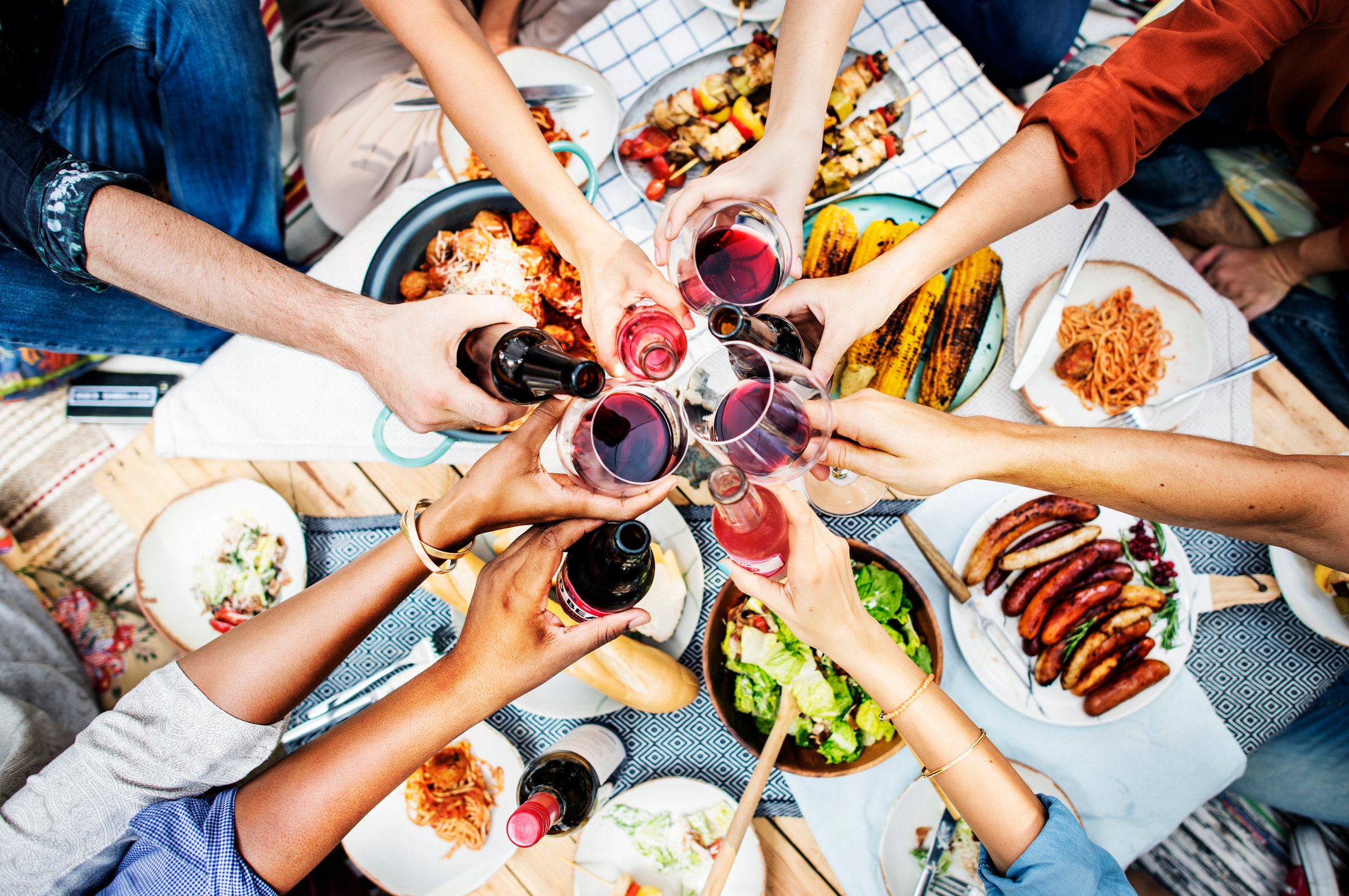 A group of friends clink their drinks together over a big meal.