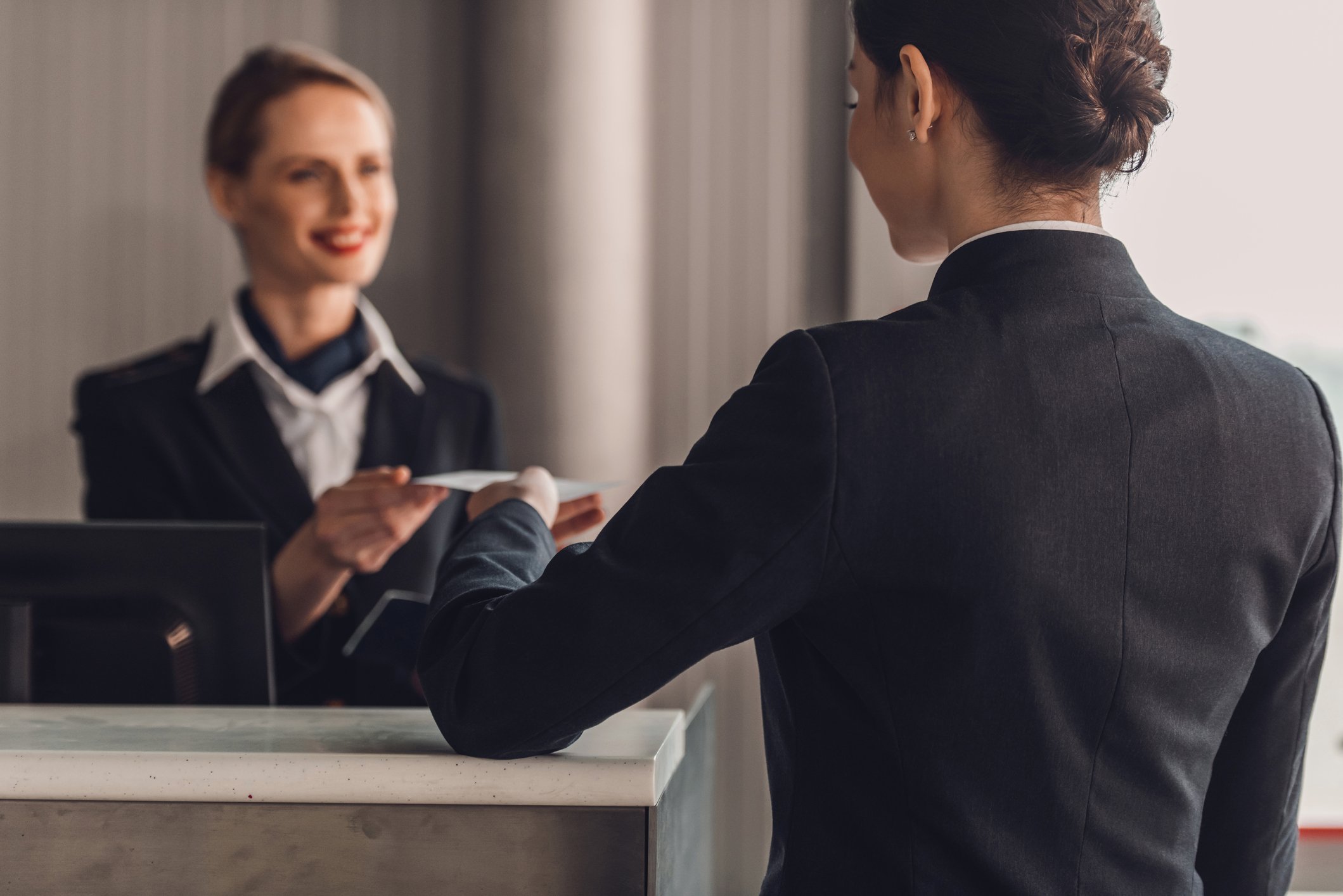 A businesswoman checks in at a hotel lobby reception.