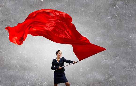 A businesswoman waves a red flag.