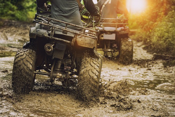 Two off-road vehicles moving through the mud.