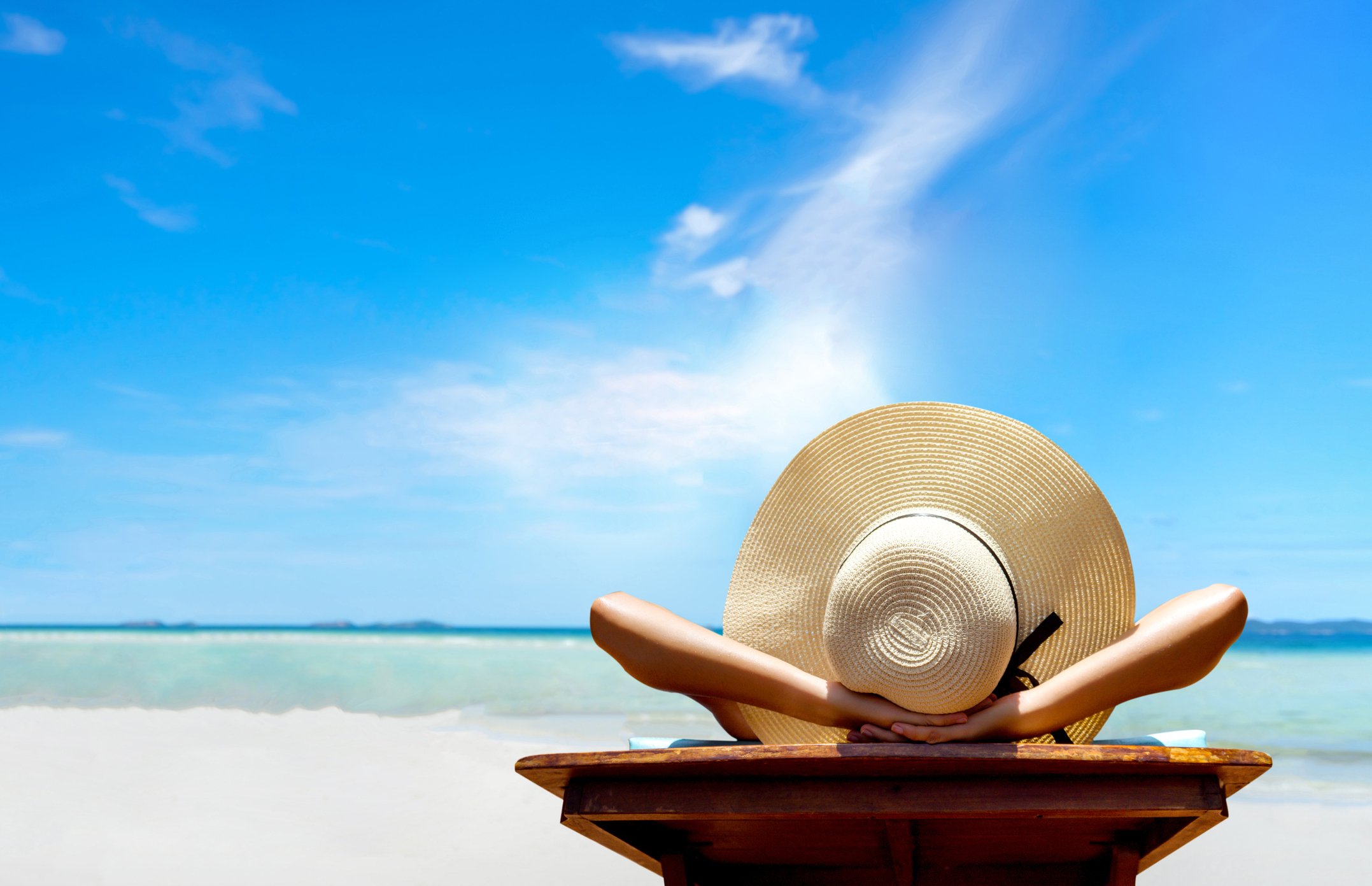 Woman in large straw hat lying down on beach
