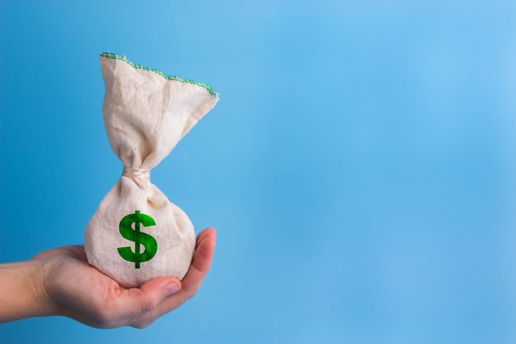 A hand holding out a canvas sack with a dollar sign on it.