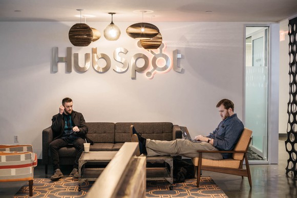 Two men sitting in front of a HubSpot sign.