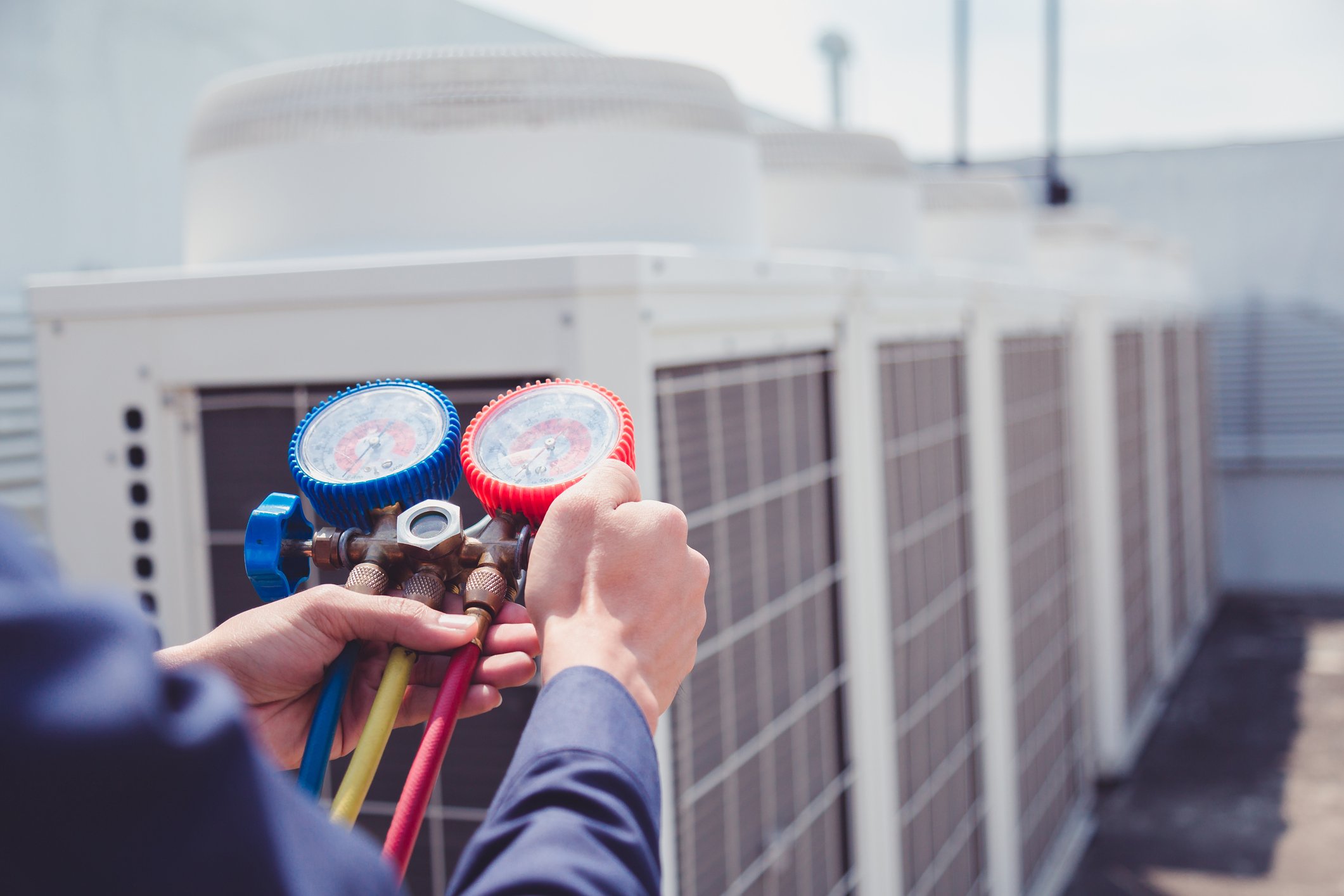 An air conditioner repair technician checks the levels on an outdoor unit.