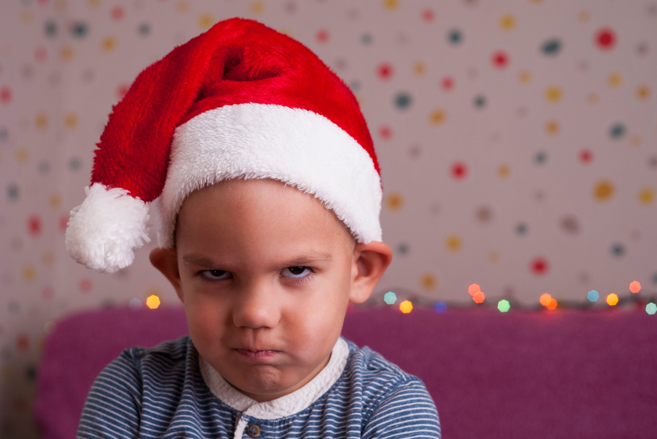 Frowning child wearing Santa elf hat.