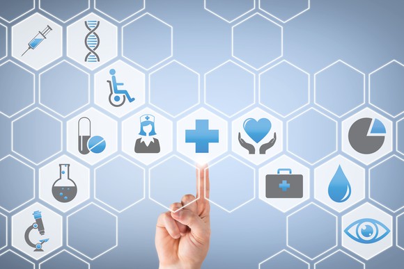 Finger pointing to blue cross in the midst of multiple healthcare-related icons