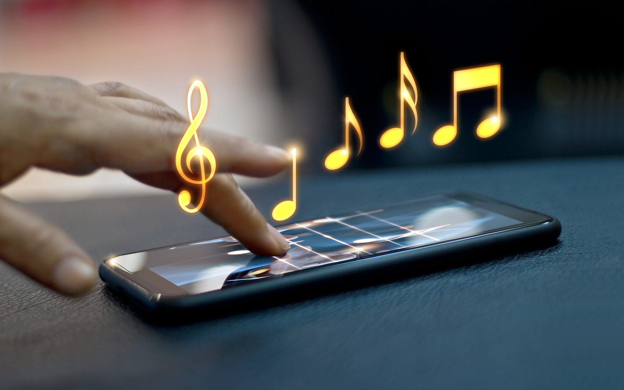 Hand tapping smartphone playing musical notes