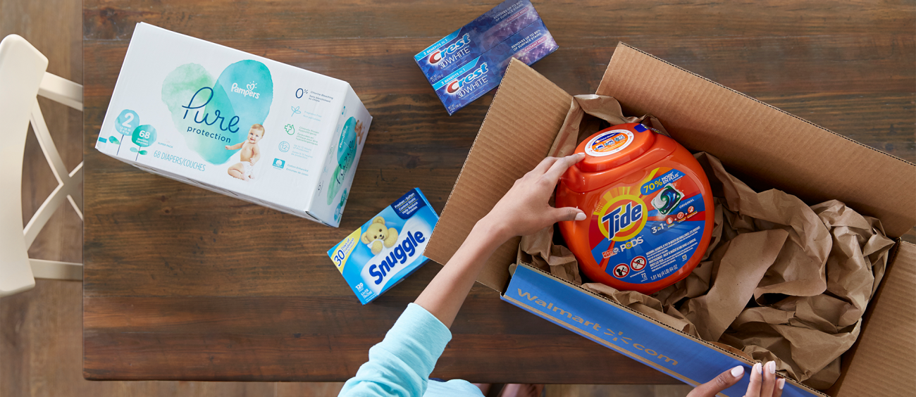 A woman hands pulling items out of a shipping box with the Walmart logo printed on the side.
