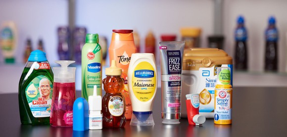 Various plastic containers from AptarGroup with products including soap, honey, mayonnaise, and eye drops. 