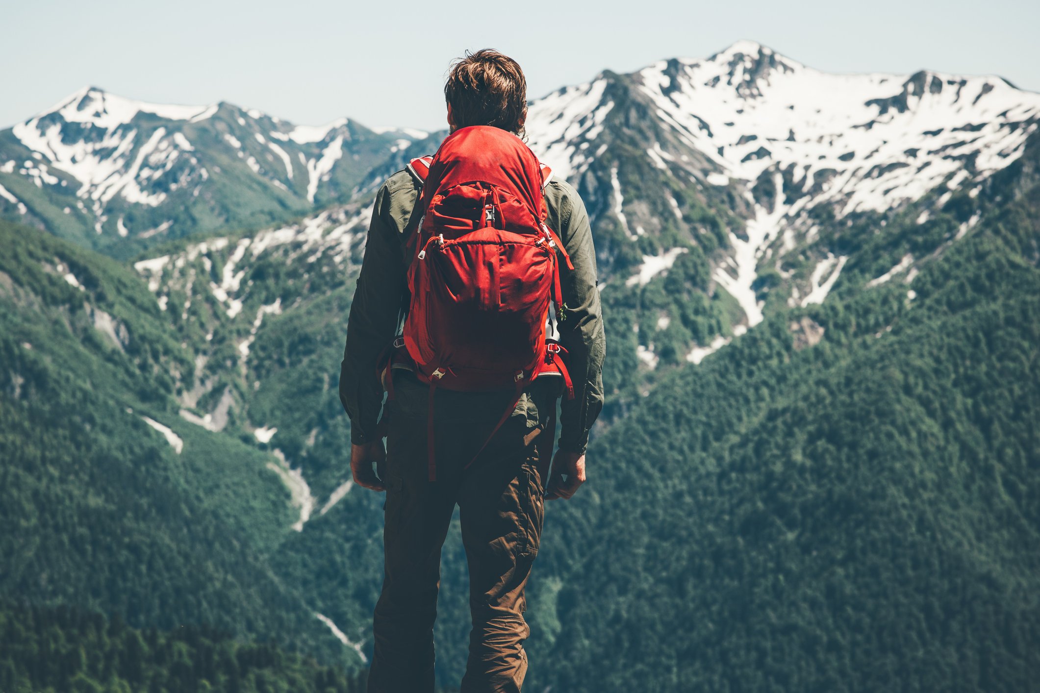 Man hiking in mountains with red backpack