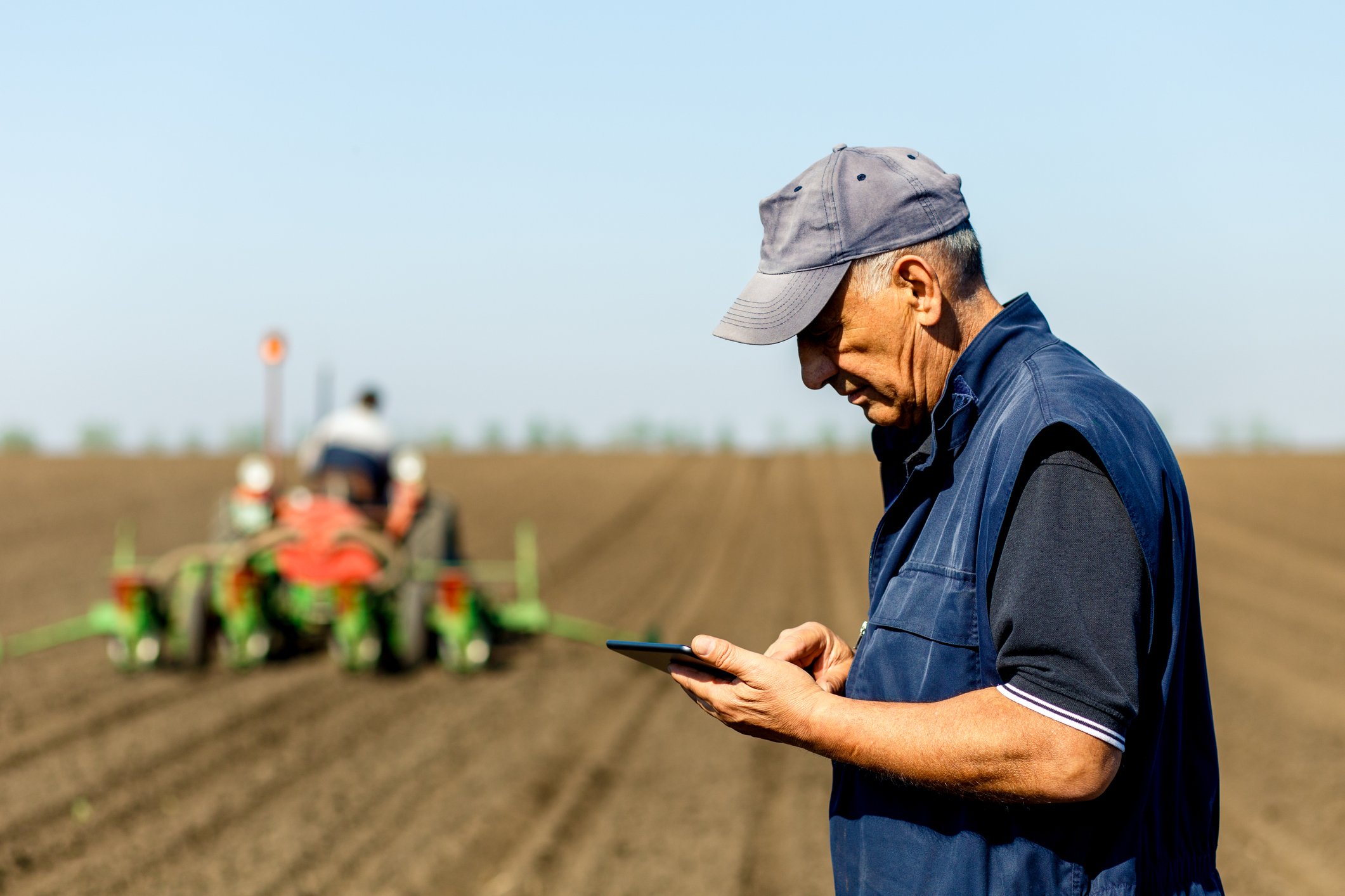 A farmer in a field with a tractor behind him