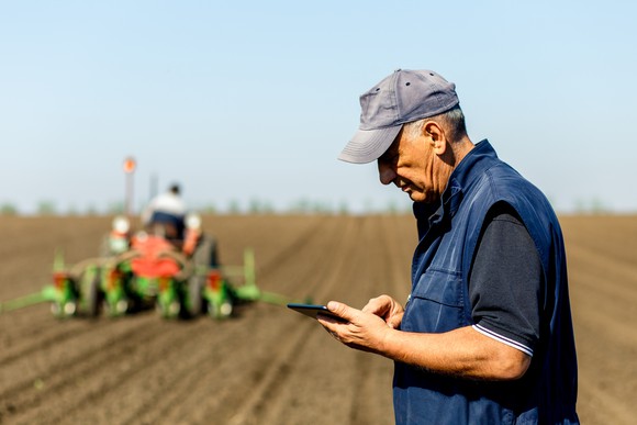 A farmer in a field with a tractor behind him
