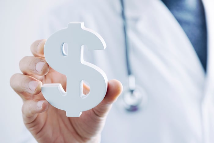 Doctor holding a dollar sign.