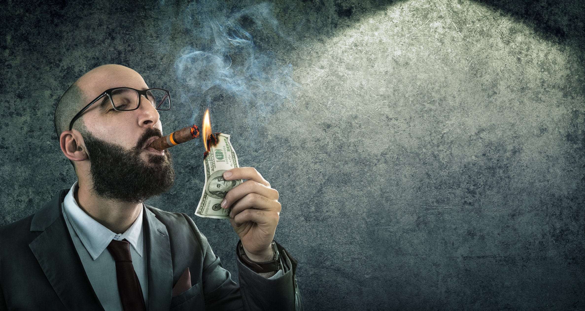 A man smokes a cigar by burning cash.
