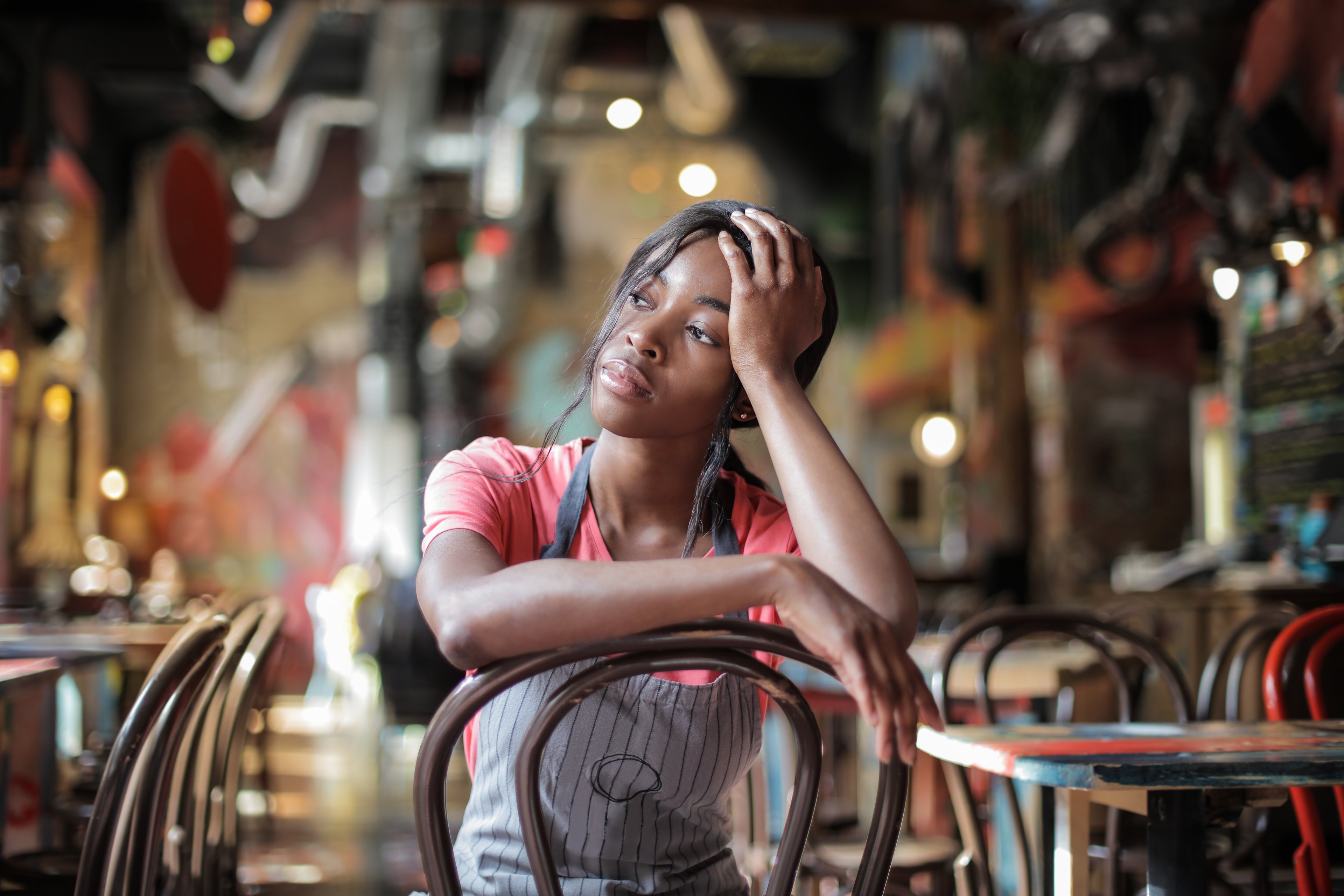 A woman who works at a cafe sitting down looking away