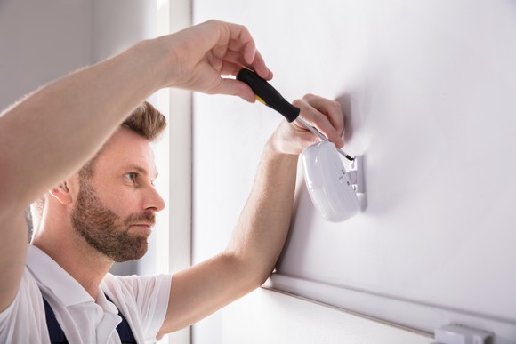 Technician installing a sensor on a wall. 