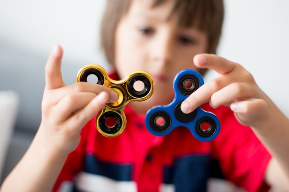 A boy plays with two spinners.