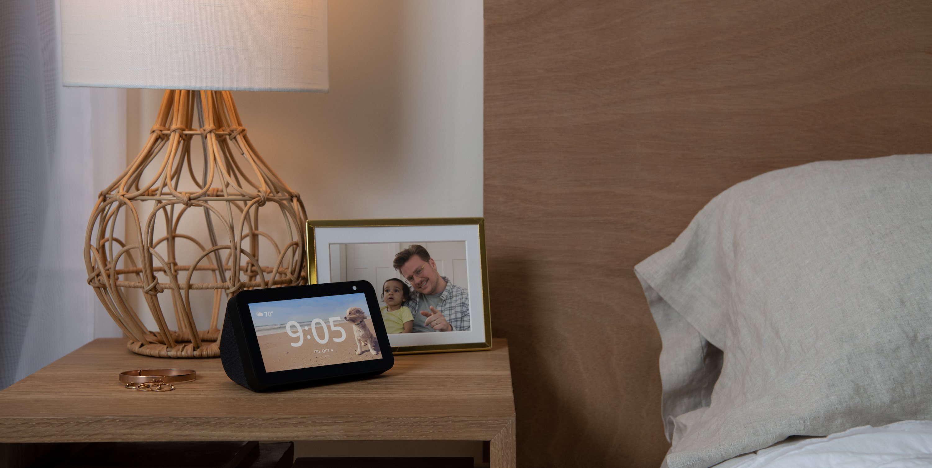 Echo Show 5 on a nightstand next to a lamp and a framed photo
