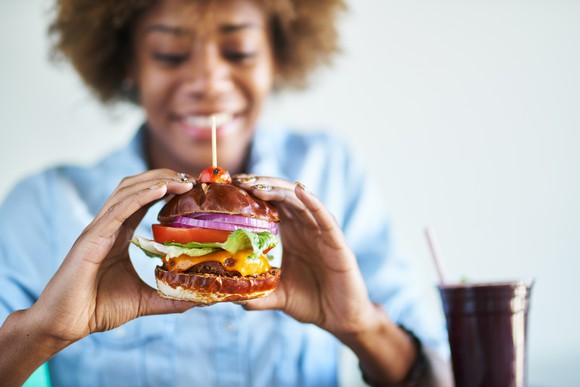 Smiling woman about to eat a vegan cheeseburger