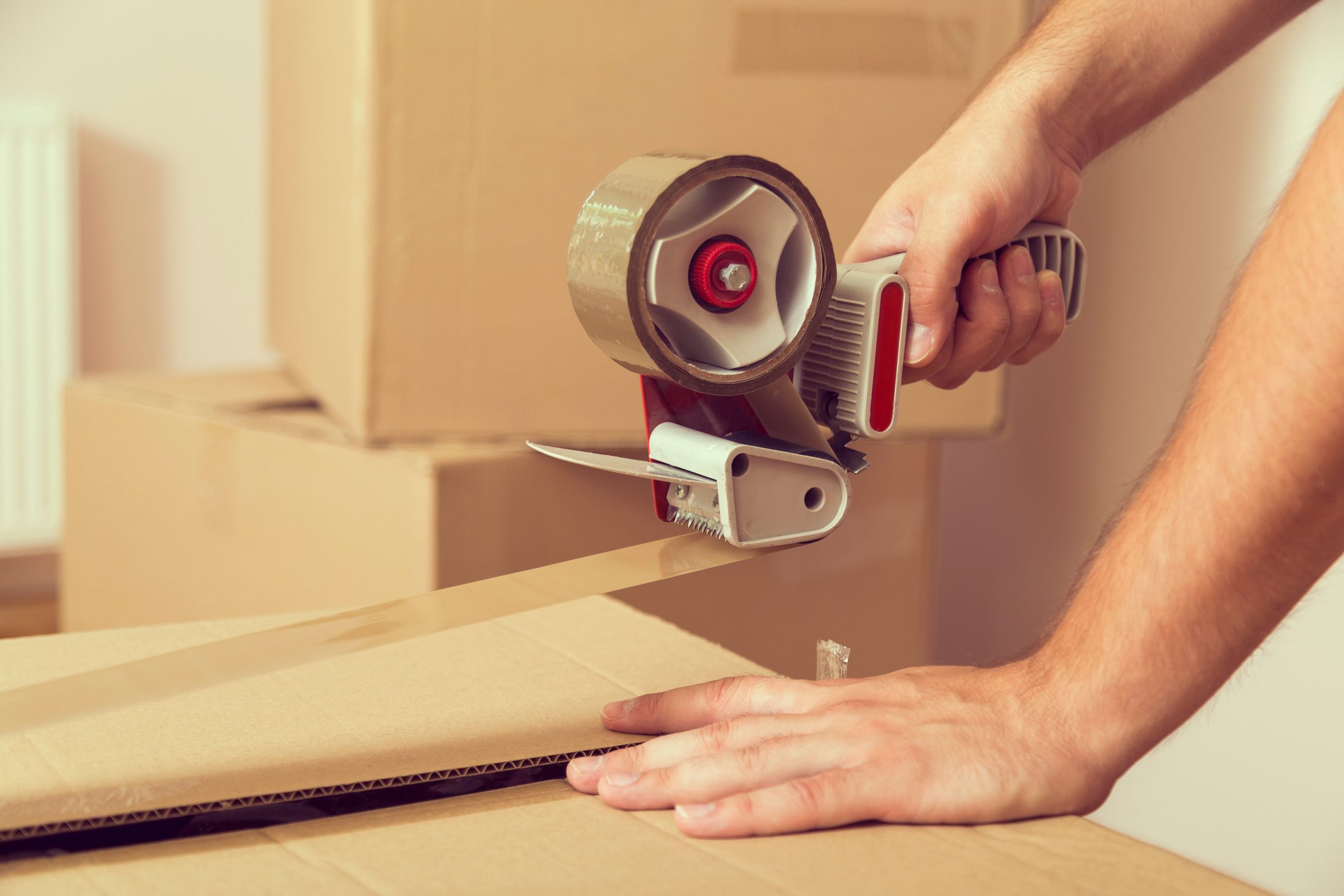 Man rolling packing tape across cardboard box