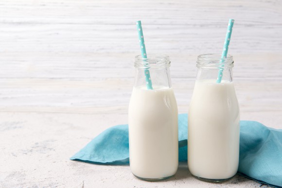 Two jars of milk with one straw in each.