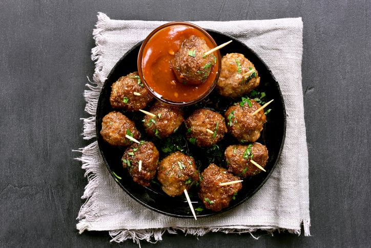 Meatballs made from cultured meat, on a platter, with dipping sauce.