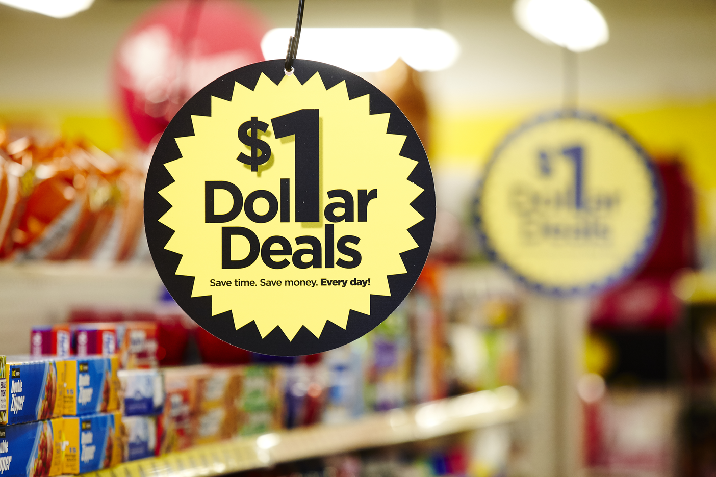A sign in a dollar store aisle that says $1 Dollar Deals.