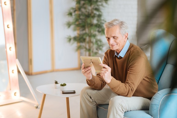 Older person looking at a framed picture.
