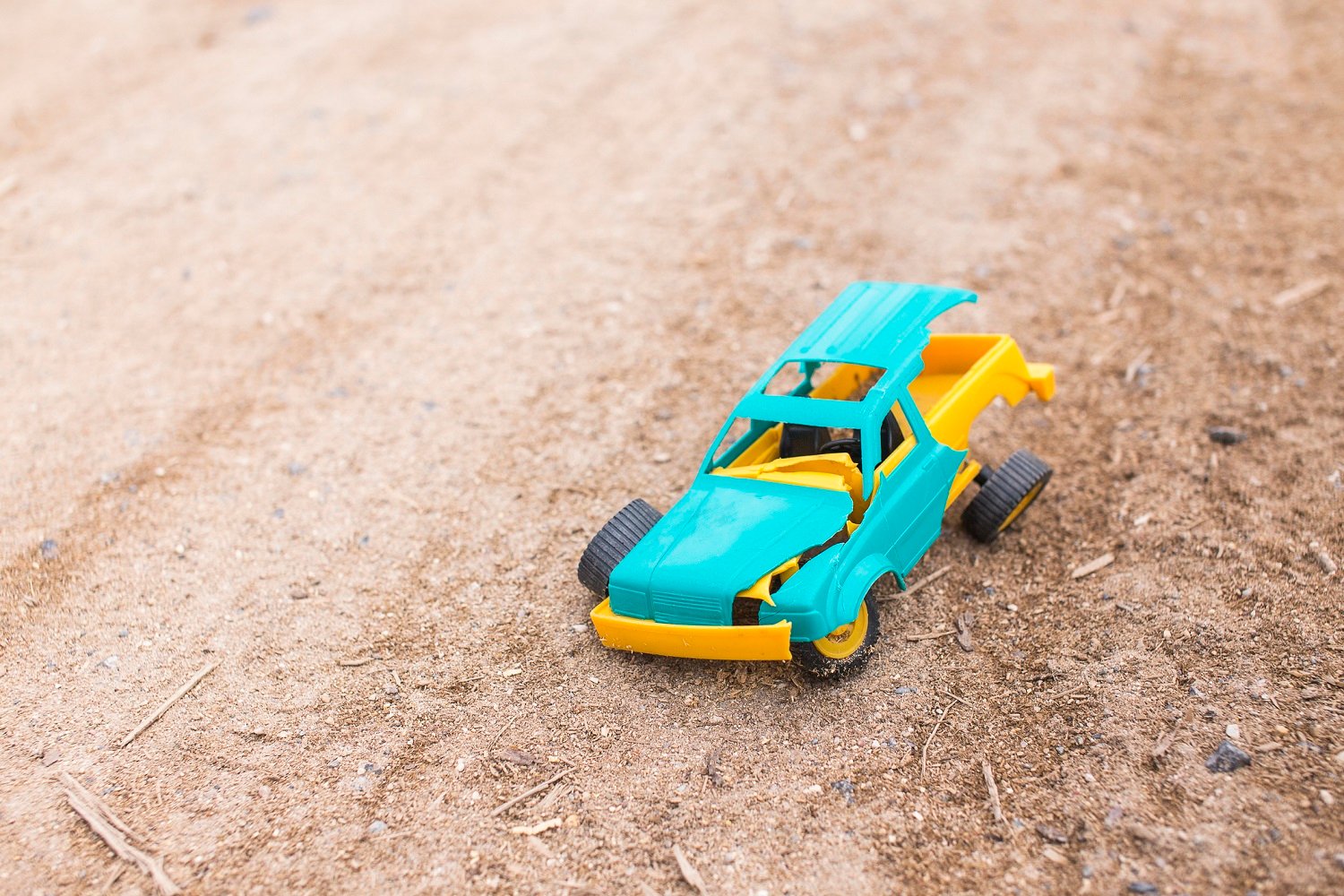 A plastic toy truck, broken and lying on the ground
