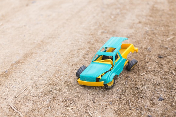 A plastic toy truck, broken and lying on the ground