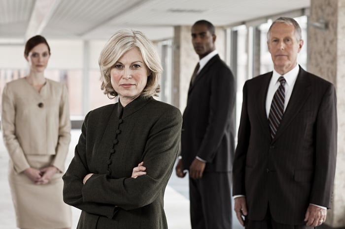 Two men and two women in business suits with serious expressions