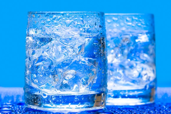 Tw glasses of ice water with blue background.