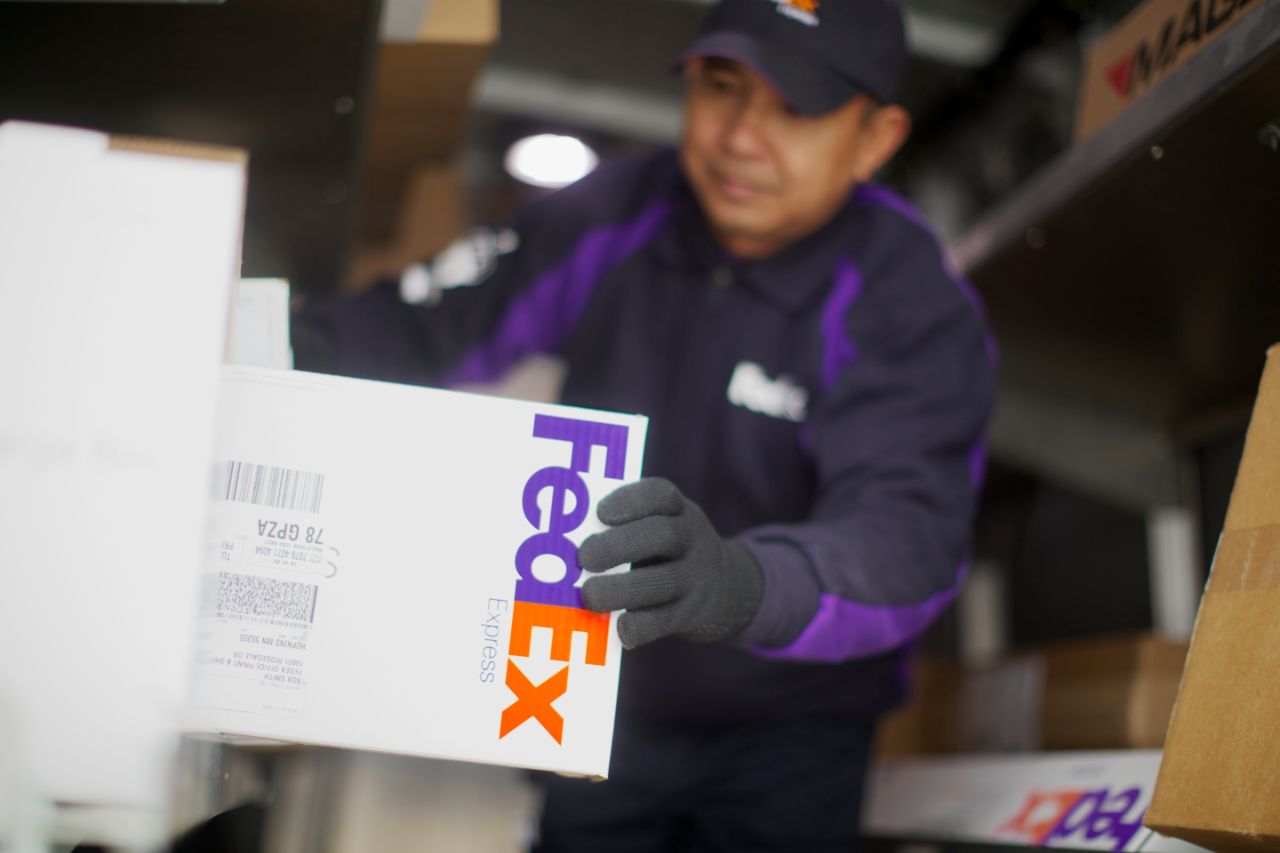 A FedEx worker handling a package in a delivery truck.