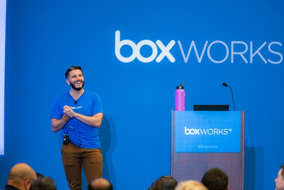 Man on stage in front of a crowd, with Box Works logo behind and on podium.