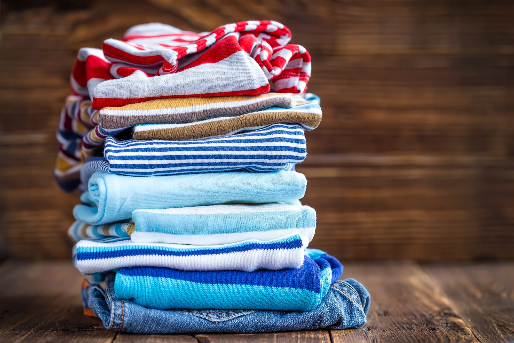 Stack of folded children's clothing on a wood floor.